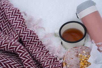 A flat lay image featuring a red and white zigzag patterned blanket, a pink thermos, an enamel mug...