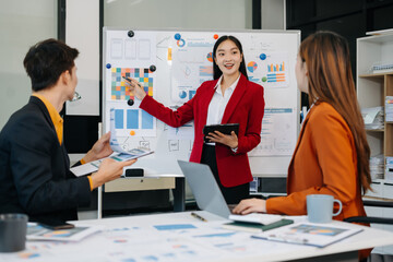 Group of professionals participating in meeting or workshop. presenter standing near flip chart give presentation interact with participants, attendee ask questions, share opinion or solutions.