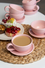Pink ceramic cup and saucer on light dining table in dining room