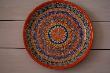 A beautiful ceramic dish with oriental patterns lies on a table made of white boards. Top view.