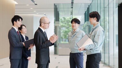 ロビーで話をするビジネスマンと作業服を着た男性