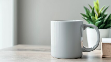 Fototapeta premium A white coffee mug sits on a wooden table next to a potted plant