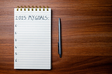 Notepad with text 2025 My Goals, on wooden surface. Priorities and goals for 2025