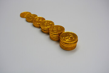 Beautiful, large gold coins, cents with a dollar $ sign are located on a white plastic background. Money candies, a chocolate bar in a gold metal shell.