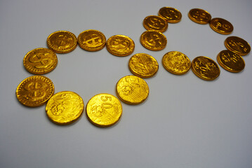 Beautiful, large gold coins, cents with a dollar $ sign are located on a white plastic background. Money candies, a chocolate bar in a gold metal shell.