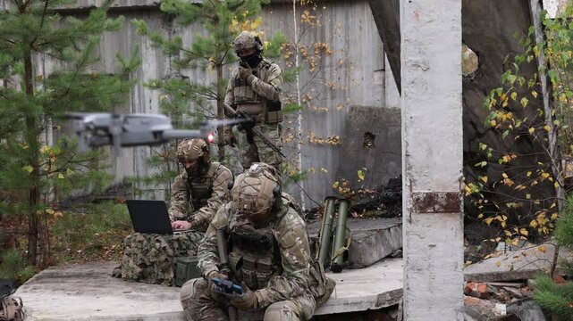 Modern army soldiers using aerial drone for artillery guidance and scouting view enemy positions in military operation.