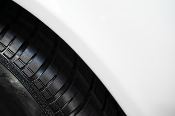 detail of car wheel black rubber tire on the front wing fender of white car