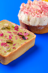 closeup of a Pistachio and Passion Fruit Tarts with Whipped Cream on a Vibrant Blue Background