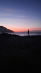 silhueta de homem caminhando na praia no nascer do sol, em ubatuba, são paulo