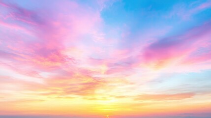 Obraz premium Pastel sunset sky with soft pink and blue clouds over a glowing yellow horizon.