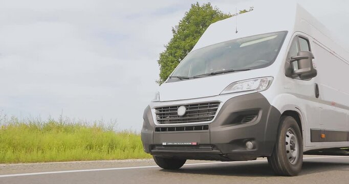 Cargo minibus drives on the highway in sunny weather. White delivery van driving along the highway. Express delivery