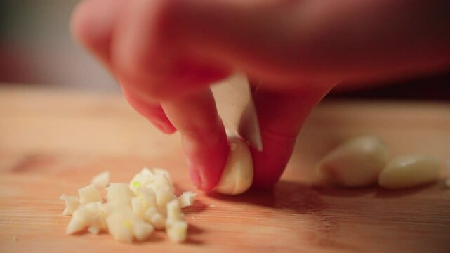 Cutting garlic by hand with a knife on a cutting board