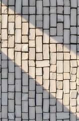 Sunlit off-white rectangular tile wall.