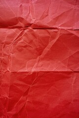 Red paper with a rough texture. The paper is crumpled and torn, giving it a worn and aged appearance. The red color of the paper contrasts with the rough texture, creating a sense of depth
