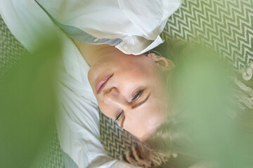 Relaxed caucasian female lying on zigzag pattern rug with green leaves for a natural soothing...