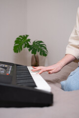 Young woman playing electronic piano at home. A red-haired girl learns to play the synthesiser.