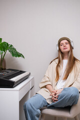 Young woman playing electronic piano at home. A red-haired girl learns to play the synthesiser.