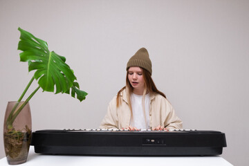 Young woman playing electronic piano at home. A red-haired girl learns to play the synthesiser.