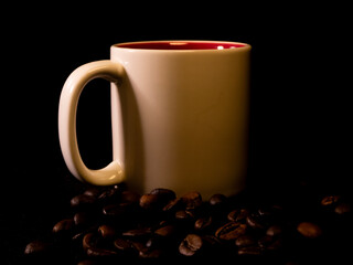 White ceramic coffee mug with coffee beans on a black background