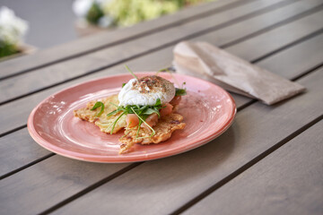Delicious avocado and smoked salmon breakfast with poached egg on crisp hash browns on outdoor...