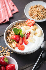 Yogurt and granola bowl with strawberries, banana and almond flakes