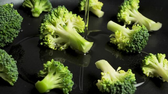 Pouring vegetable oil into a frying pan with green broccoli pieces for frying and cooking vegetarian broccoli omelette. Olive oil flow into the frying pan. Healthy lifestyle. Healthy eating