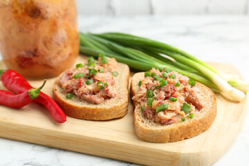 Sandwiches with canned meat, green onions and chili peppers on white marble table, closeup