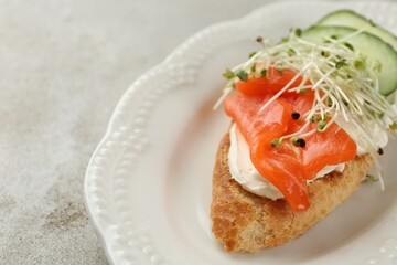 Delicious bruschetta with salmon, cream cheese and cucumber on light table, closeup. Space for text