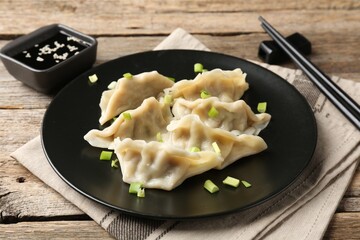Delicious gyoza dumplings with chives served on wooden table, closeup