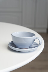 Ceramic mug with saucer on kitchen light table