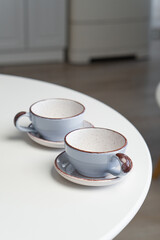 Ceramic mug with saucer on kitchen light table