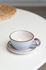 Ceramic mug with saucer on kitchen light table