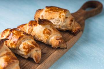 Croissants on a wooden board on a blue background.