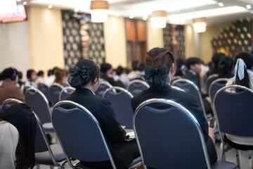 A large group of people seated in rows of chairs, attentively participating in a formal event held...