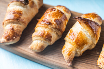 Croissants on a wooden board on a blue background.