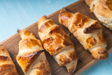 Croissants on a wooden board on a blue background.