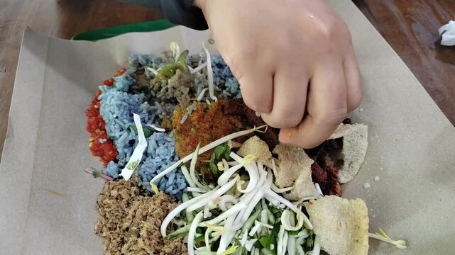Nasi Kerabu, a traditional Malay dish from Kelantan, Malaysia, featuring blue rice, fresh herbs, and succulent grilled meat.