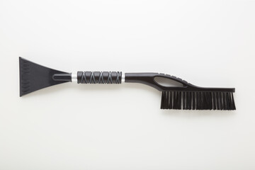 New dark black car brush with scraper for snow and ice cleaning on light gray table background. Closeup. Top down view.