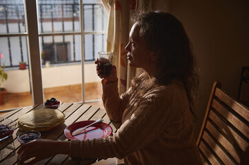 Woman enjoying breakfast in peaceful morning light by a window