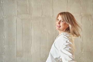 Fototapeta premium Caucasian female adult smiling with wind in hair against textured wall.