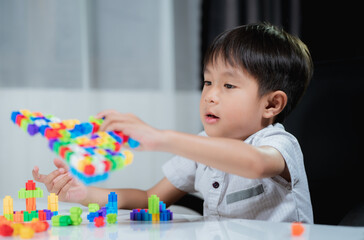 A little Boy  playing with plastic bricks in the living room, little Boy  playing with colorful toys.