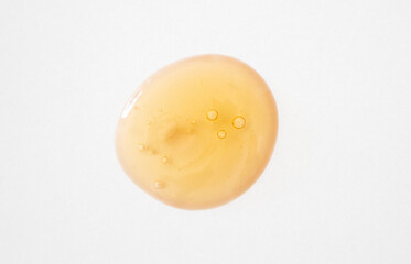 Serum with snail mucin and ginseng drop smear with bubbles close-up. Beauty product sample on white background.