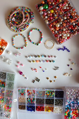 Friendship bracelet spelled with letter beads. Colorful handmade bracelets and various jewelry making supplies. Top view, white background.