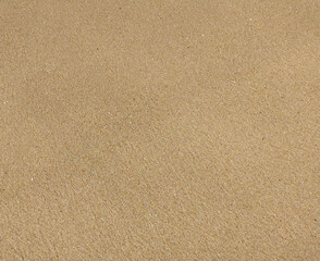 Fine golden sand covering a beach during a sunny day with clear skies, creating a serene and tranquil atmosphere for relaxation