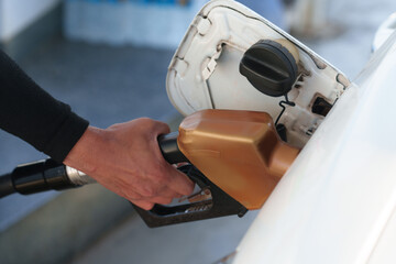 Close-up of a gas station attendant's hand and a gold fuel nozzle.