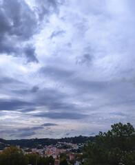 Dramatic cloud formations over a hillside town in the late afternoon sunlight highlighting the landscape's beauty