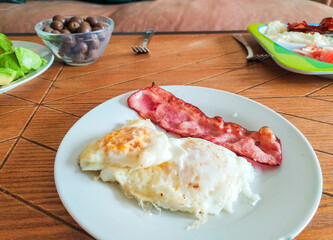 Closeup of a delicious breakfast plate featuring fried eggs and crispy bacon.  Perfect for menus, blogs, or articles about healthy eating and morning meals.
