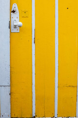 Bright yellow door with white trim providing a colorful entrance to a charming building in a sunny location