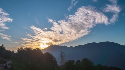 Amazing summer landscape with dramatic foggy sunset. Sun rays emerge through the clouds in the mountains at sunset.