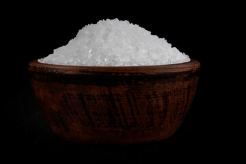 Clay cup with salt on a black background. table salt.